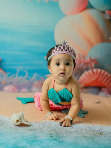 This shot captures the crawling milestone within the mermaid theme. The perspective from the water's edge adds a creative touch to this 11-month-old's portrait.