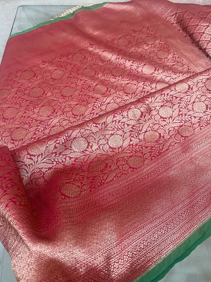 Here is the full view of a red Banarasi silk saree with a green border. The pallu is covered in a dense floral jaal weave.