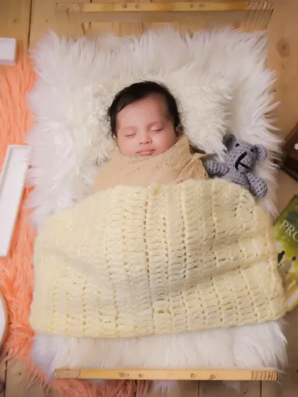 A milestone shot for a two-month-old baby, sleeping peacefully on a fur rug with large "TWO" letters to mark the occasion.