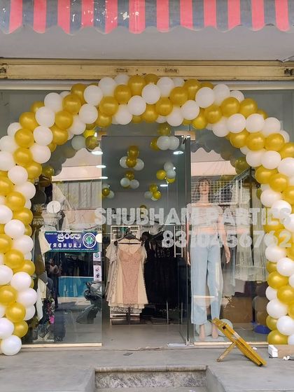 A gold and white balloon arch for the opening of a new clothing boutique.