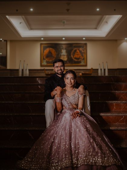 A classic, elegant portrait of the couple seated on the stairs during their Sangeet night. The soft lighting creates a romantic and timeless feel.