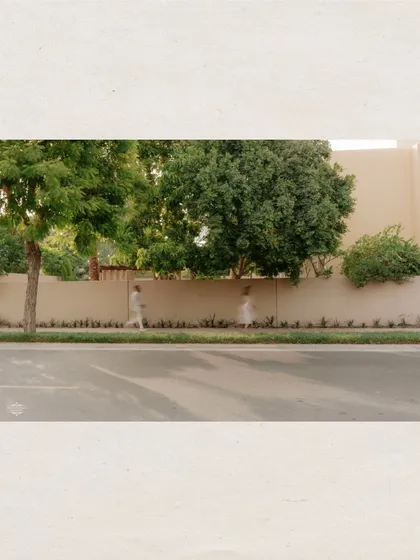 A wide, atmospheric shot of a couple walking along a tree-lined street in Dubai. This photo captures a sense of place and a quiet, everyday moment.