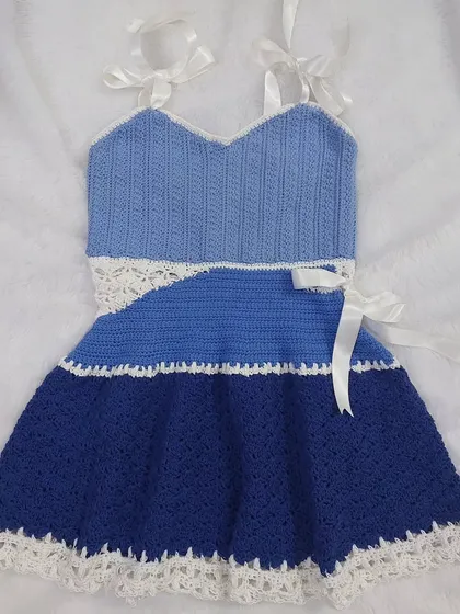 A flat-lay of the Aviva Dress, showcasing the full design with its halter straps and A-line skirt.
