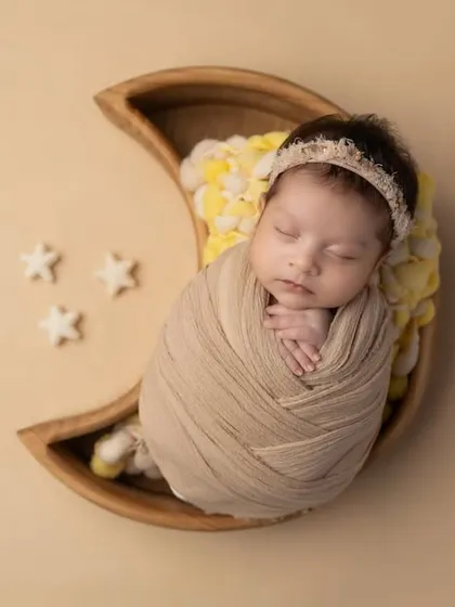 A sweet, swaddled baby dreaming amongst the stars. I use beautiful props like this wooden moon bowl to create whimsical and peaceful scenes, always ensuring your baby is snug and secure.