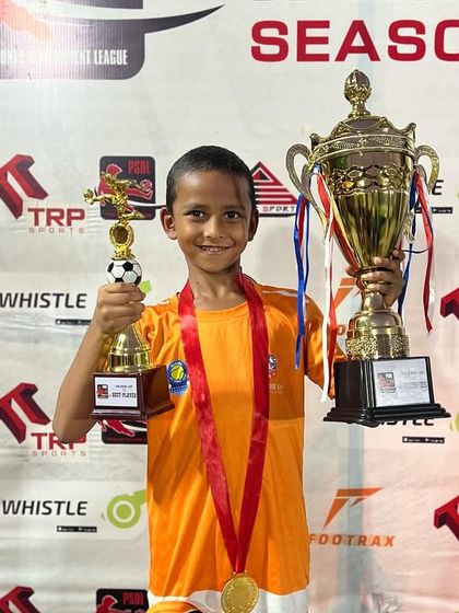 A U7 player holds his trophies high after a successful PSDL season.