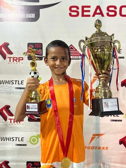 A U7 player holds his trophies high after a successful PSDL season.