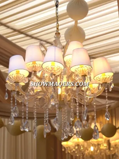 A close-up of a beautiful chandelier used in the outdoor setup. The combination of classic lighting fixtures with draped fabric creates a sophisticated, ballroom-like feel in an open-air setting.