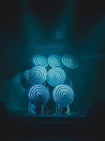Dancers using hypnotic, spiraling props that glow under the stage lights, adding a surreal and artistic element to the couple's performance.