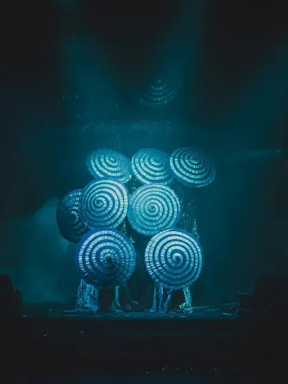 Dancers using hypnotic, spiraling props that glow under the stage lights, adding a surreal and artistic element to the couple's performance.