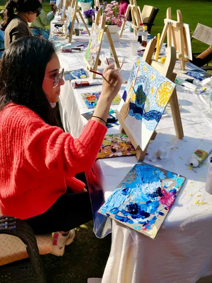 A participant engrossed in painting her version of 'Starry Night' at our outdoor art party.