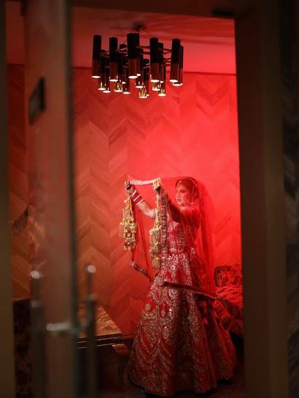 The grandeur of a bridal entry. This wide shot captures the bride in her magnificent red lehenga, holding her kalire, ready to make her way to the ceremony.