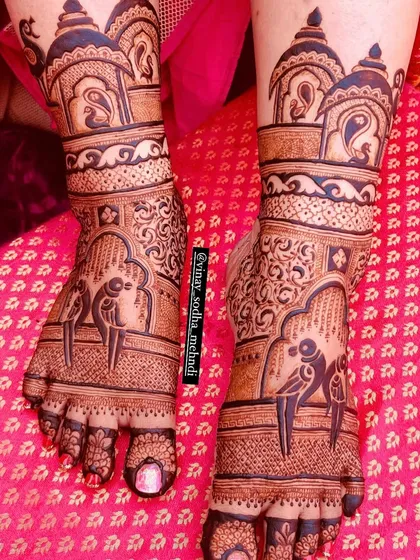 A beautiful bridal foot design with parrots perched inside arched windows. The top of the feet are adorned with architectural domes, creating a complete story.