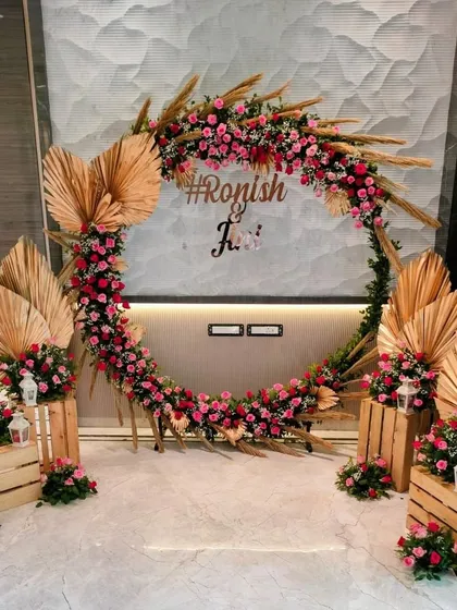 For a modern and personal touch, we design trendy photo backdrops like this circular arch. Combining rustic dried palms with vibrant pink roses and a custom hashtag, it becomes a favorite spot for guests to capture memories.