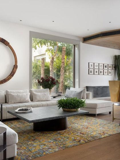 This view of the casual lounge showcases the iconic 'Tango Bar' from our Koko collection, a sculptural brass piece that serves as the room's protagonist. The circular wood installation on the wall adds another layer of organic form, balancing the clean lines of the space.