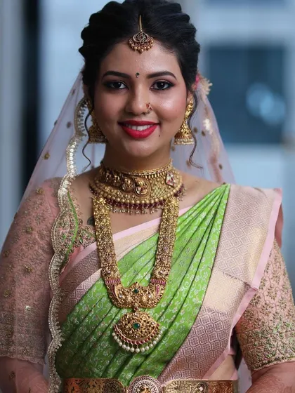 A portrait of bridal beauty. The sheer veil complements the custom-embroidered blouse and the vibrant colors of her South Indian wedding saree.