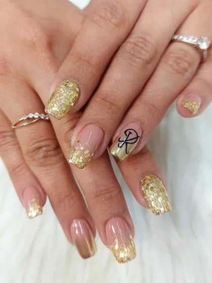 We offer personalized nail art, like adding a custom initial. This celebratory set features a cascade of gold glitter and a beautifully scripted initial, making it perfect for an engagement or anniversary.