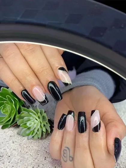 A chic and graphic design with black polish on a nude base, creating an angular, modern look.