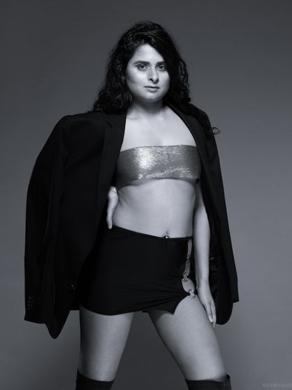 A powerful black and white fashion portrait. The combination of a blazer, metallic top, and mini skirt creates a bold, confident look.