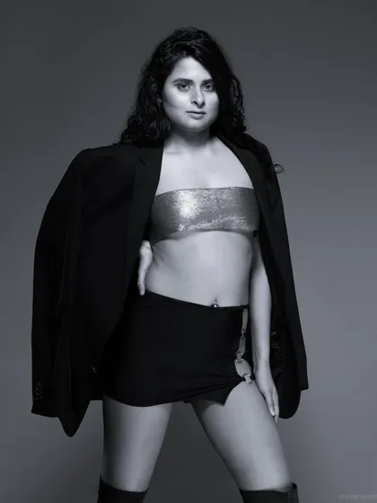 A powerful black and white fashion portrait. The combination of a blazer, metallic top, and mini skirt creates a bold, confident look.