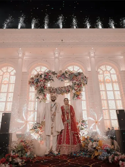 Your wedding stage is the heart of the celebration, and we make sure to capture its full splendor. This wide shot shows the couple framed by a magnificent floral heart and grand architecture, highlighting the scale of their big day.