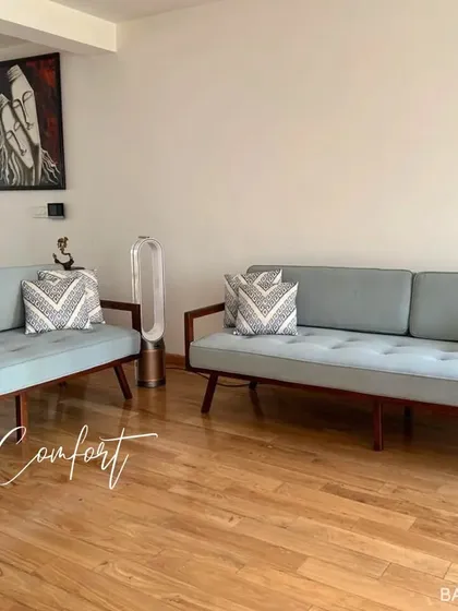 This living room setup features mid-century modern style sofas with clean lines and wooden frames, creating a relaxed and timeless look.