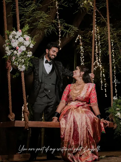 A whimsical reception photo of the couple on a decorated swing, surrounded by fairy lights.