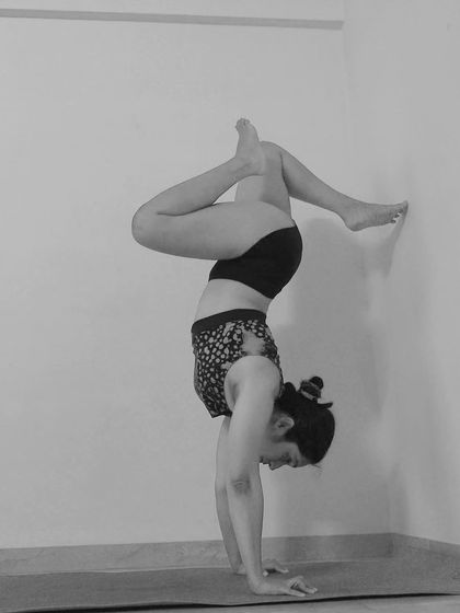 A still shot of a wall-assisted handstand variation. Using the wall is a key tool I teach to help you understand alignment and build strength safely.