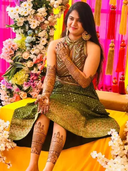 A beautiful bride posing with her hand and leg mehendi. The designs are coordinated, and she looks absolutely radiant for her mehendi ceremony.