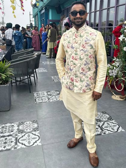 A classic combination for a daytime event. This client wears a cream-colored kurta and pajama with a vibrant floral print jacket.