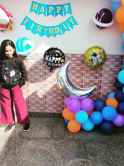 Another shot of our happy client at her astronaut-themed birthday party. The setup includes a colorful balloon garland with planet and rocket ship foil balloons.