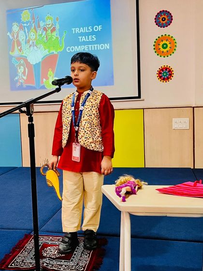 Dressed as Aladdin, a student uses props like a magic lamp and carpet to tell the classic story during the 'Trails of Tales' competition.