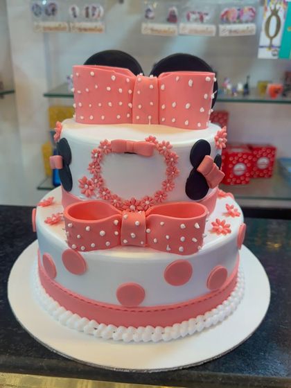 A beautiful two-tier Minnie Mouse cake with large pink fondant bows and polka dots. This design is perfect for a bigger celebration, offering a grand centerpiece for the party.