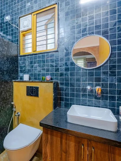 The bathroom combines bold black slate tiles with a warm yellow sandstone accent wall, creating a striking contrast.