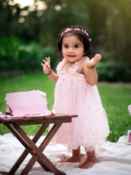 So proud of her cake-smashing work. This photo captures the happy and messy aftermath of a successful first birthday cake smash in the garden.