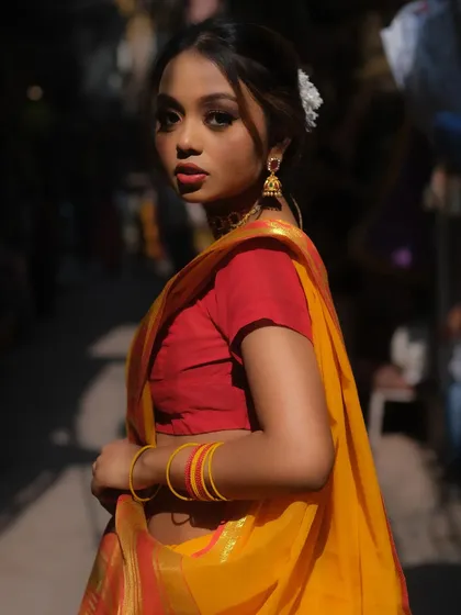 A beautiful and soft traditional look perfect for a pre-wedding photoshoot or daytime event. The makeup features a subtle smokey eye and a bold red lip that stands out against the bright yellow saree, with a flower in the hair for a classic touch.