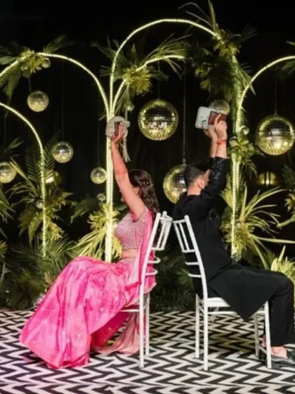 Fun and games during a Sangeet ceremony. The couple participates in the shoe game on a stylishly decorated stage, showing how the decor becomes a part of the celebration.