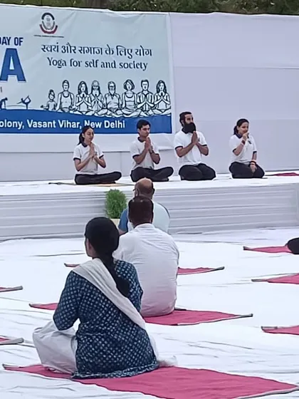 An instructor leads a large group in prayer or meditation to begin an International Yoga Day session. We always start our practice by setting an intention and cultivating a sense of gratitude.