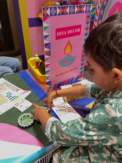 Look at the focus on this little one's face. Using sticker sheets is a fantastic, mess-free way for toddlers to participate in diya decoration and feel a great sense of accomplishment.