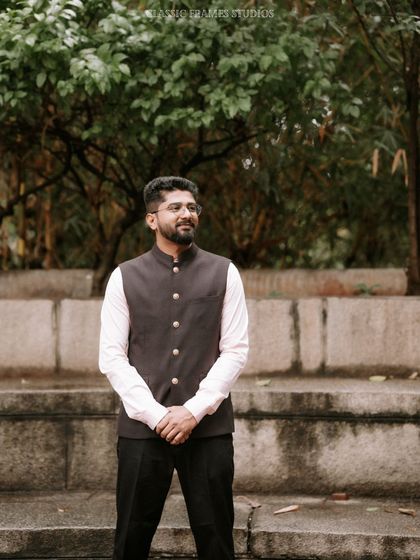 A simple and classic portrait of the groom in a Nehru jacket, waiting for the ceremony to begin. His calm demeanor is captured against a natural backdrop.
