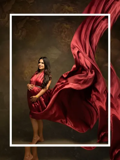 Art in motion. This studio shot uses a dramatic sweep of red fabric to create a stunning visual effect, framing the mother-to-be in a beautiful, artistic composition.
