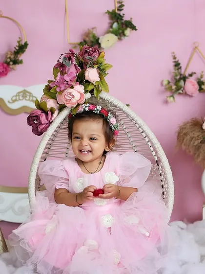 A full view of the princess-themed setup, showing the beautiful floral details, golden sequin backdrop, and the happy smile of the little girl in her swing chair.