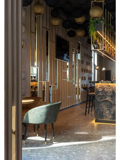 This view highlights the use of mirrored and slatted wood panels as a space divider, adding depth and visual interest. The design plays with reflection and texture to make the space feel larger.