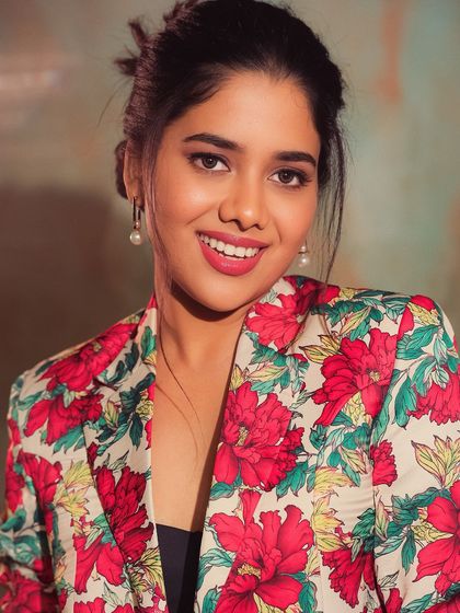A close-up portrait of Karunya, highlighting her flawless makeup and bright smile. The look is both bold and beautiful.