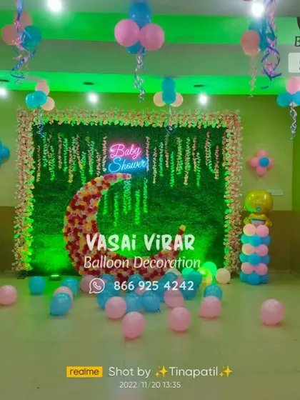 This baby shower design combines several popular elements. I use a green foliage wall as a backdrop, decorated with a floral moon, a "Baby Shower" neon sign, and classic pink and blue balloons to create a vibrant and festive atmosphere.