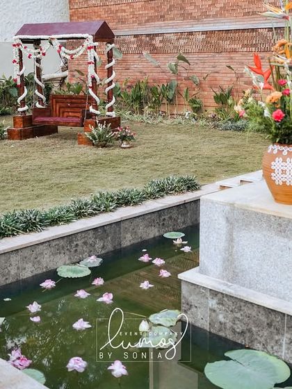 A serene garden scene with a decorative swing and a pond with floating lotus flowers.