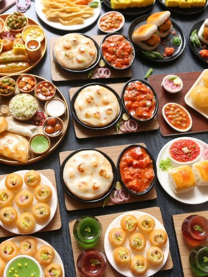 A beautiful spread of North Indian and street food miniatures, including pani puri, naan, and pav bhaji.
