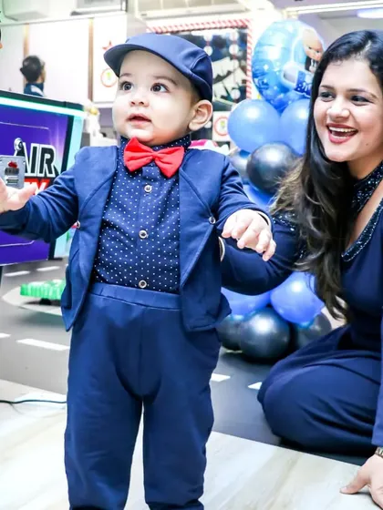 A mother helps her son, dressed smartly for his first birthday, explore the arcade area. I ensure a safe and engaging environment for even the youngest party guests.