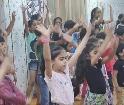 A group of children fully engaged in a dance session, with their arms raised in unison. This captures the energy and enthusiasm we foster in our kids' fitness programs.
