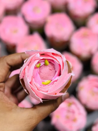 A close-up of a single Rose Rasmalai cupcake, showing the detailed piping work that creates the rose petal effect. It's a perfect blend of Indian dessert flavors and classic cupcake form.