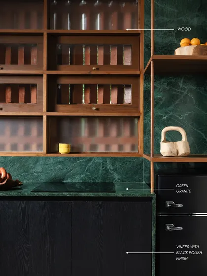 I delight in the interplay of natural materials. In this kitchen, locally sourced green granite with its dramatic veining is paired with the warmth of wood and the sleekness of a black polish finish, creating a look of understated, earthy luxury.